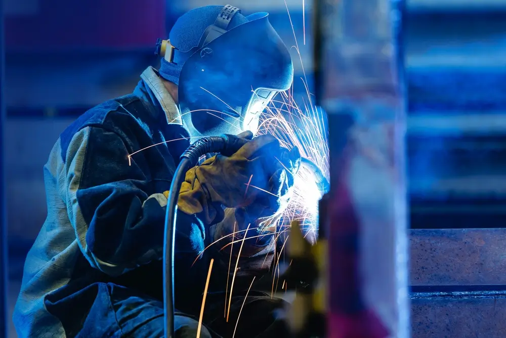Welder wearing PPE working with sparks in industrial environment