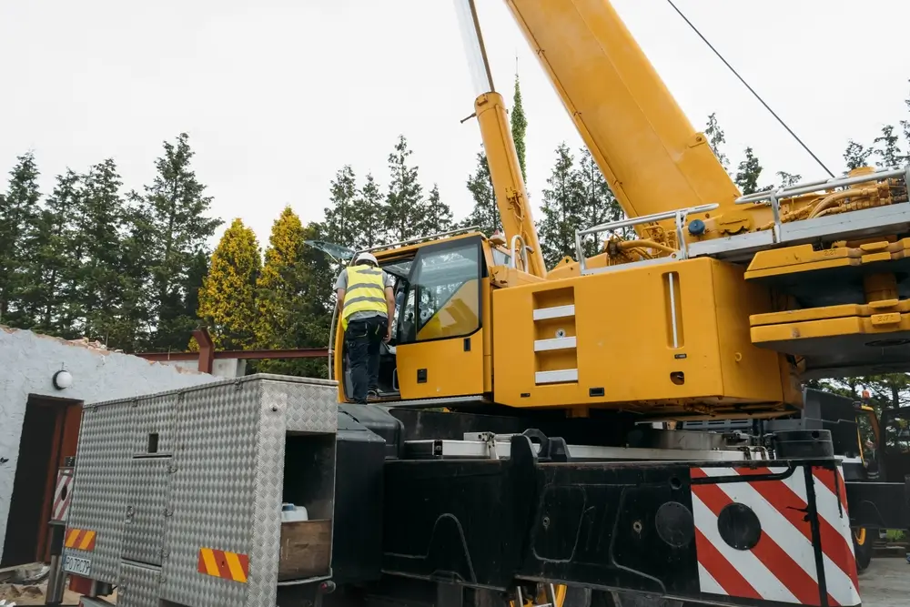 Crane operator working safely on a construction site with workers and lifting equipment